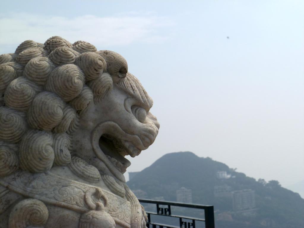Statue de lion rugissant - au loin, une colline verte