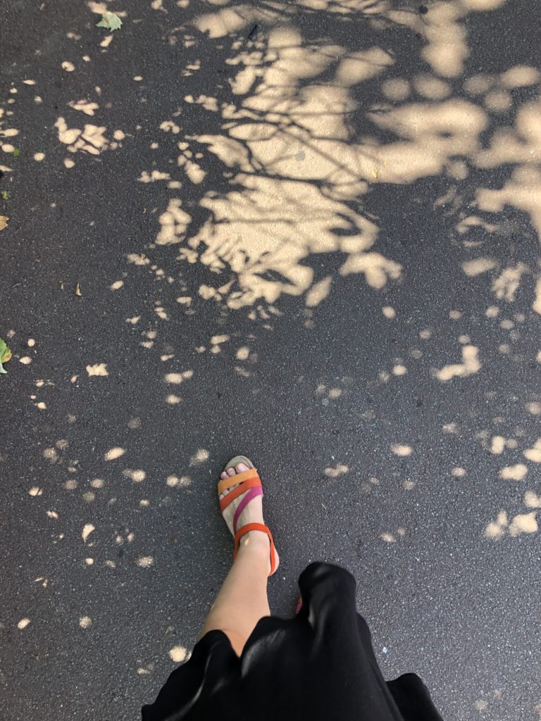 Ombres de feuillages sur le trottoir et sandales colorées