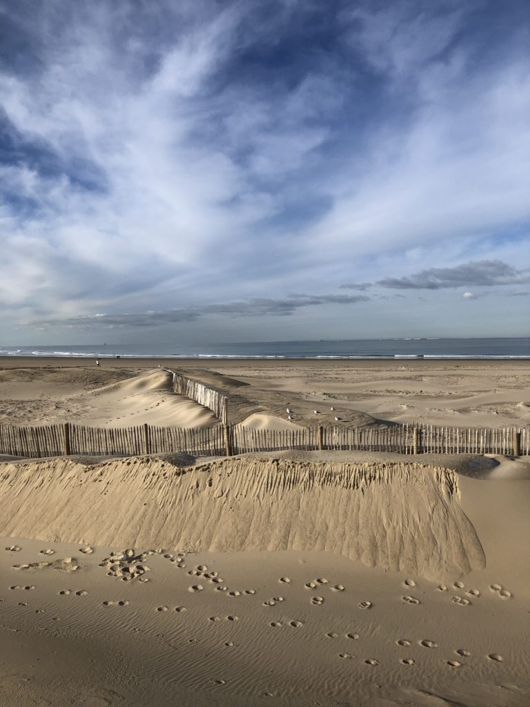 Nuages dynamiques au-dessus d'une digue de sable, la mer entre les deux