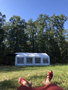 Un jardin, des arbres, un barnum, mes pieds en sandales rouges, assorties à ma robe