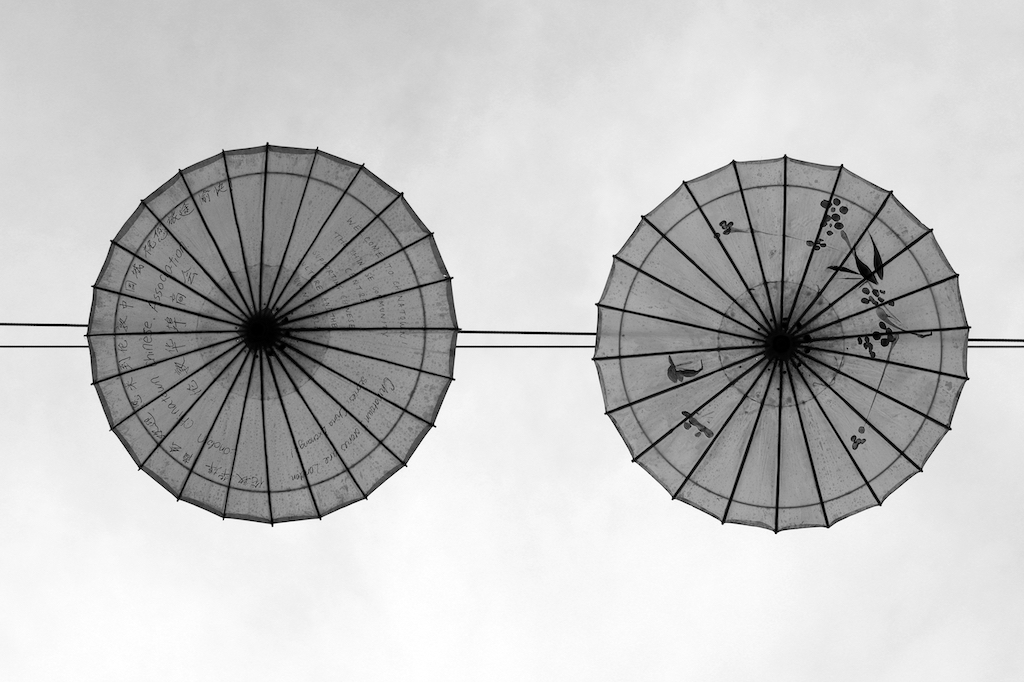 Deux ombrelles suspendues entre deux immeubles (invisibles sur la photo), prises du dessous