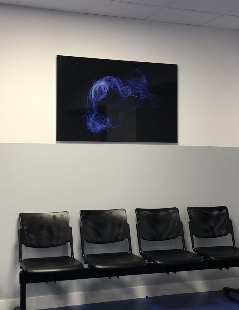 4 chaises dans la salle d'attente, surmonté par un tableau noir luisant, avec des traits lumineux bleu-violet