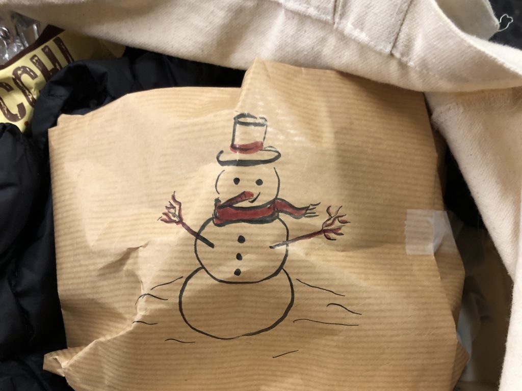 paquet cadeau kraft avec un bonhomme de neige dessiné dessus