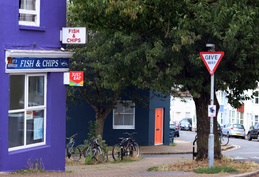 Boutique violette de Fish & chips au premier plan, puis une maison bleu sombre avec une porte orange vif