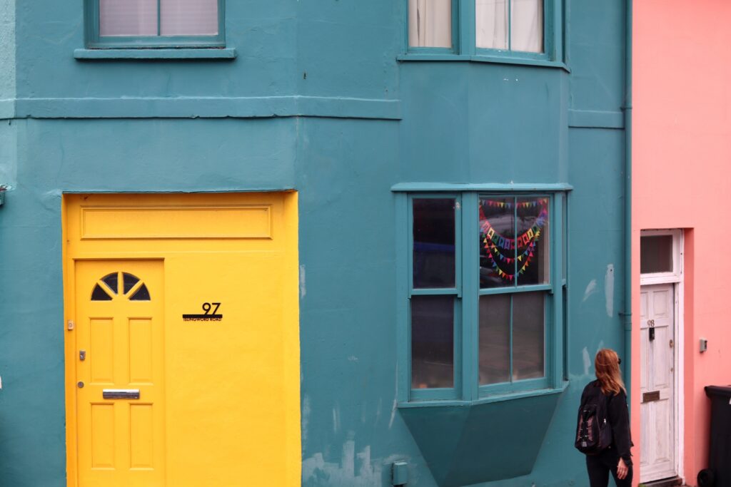 Une porte jaune vif dans une maison bleu, collée à sa voisine rose