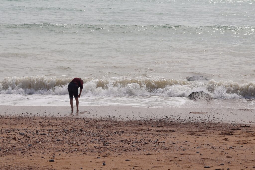 Silhouette au bord de l'eau qui relève son pantalon