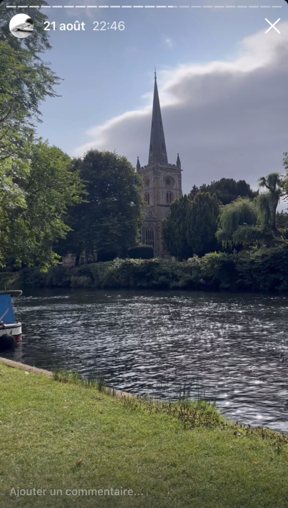 Un clocher au bord de l'Avon, avec des reflets de soleil sur l'eau.