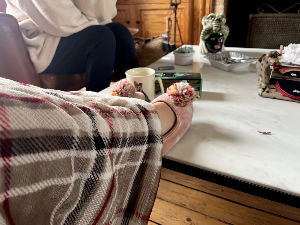 Plaid et les pieds sur la table basse, en chaussons à pompons