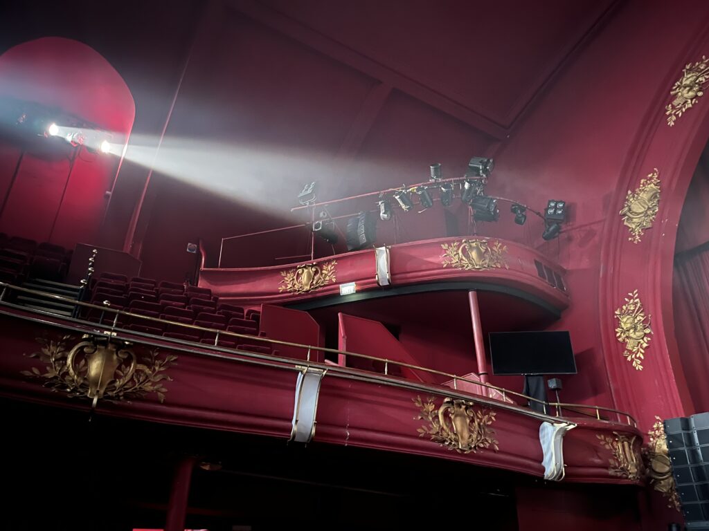 faisceau de projecteur devant la balcon d'un théâtre à l'italienne, tout en rouge